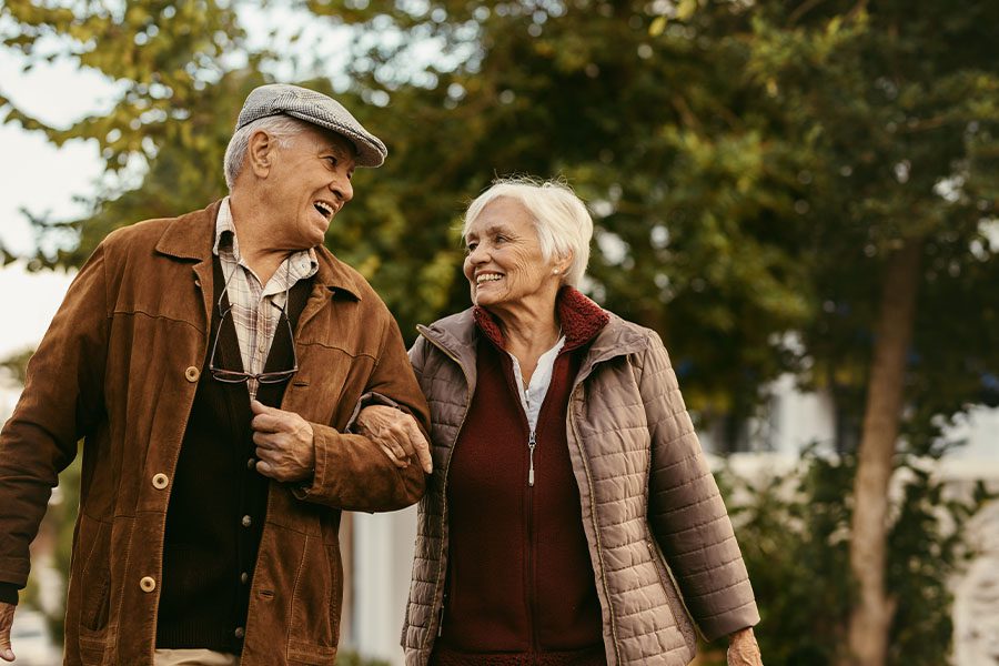 Medicare - Laughing and Smiling Senior Couple Enjoying a Walk Together on a Fall Day