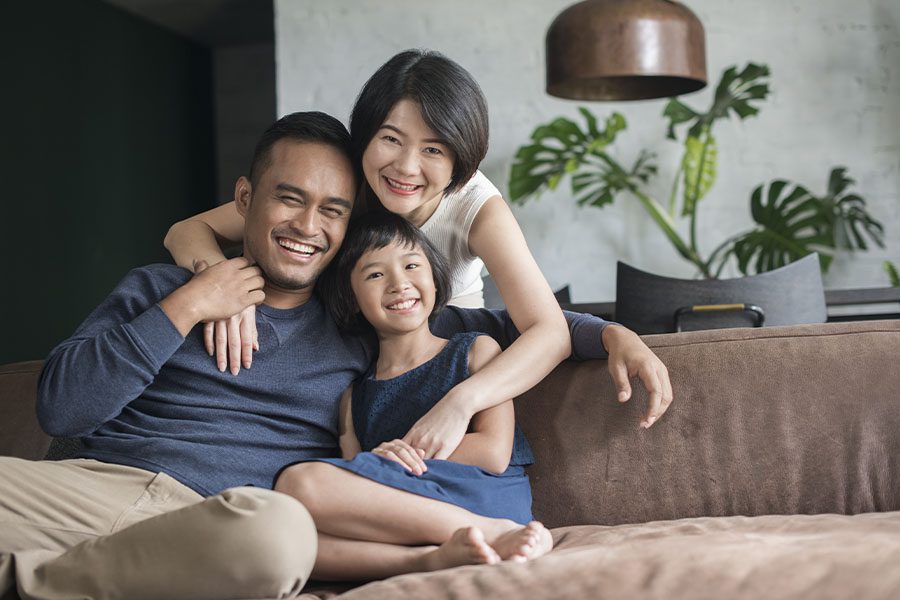 Personal Insurance - Happy Family Sitting on the Sofa Together in Their Family Living Room at Home